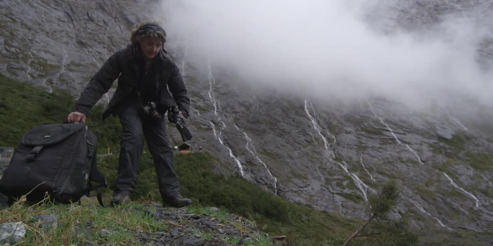 A woman sets up a camera on a mountain top