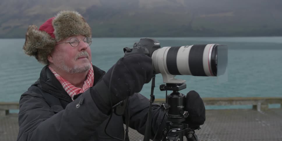 A man is using a camera with a long lens