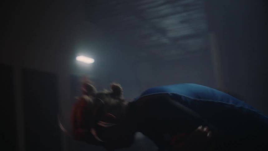 Two women grappling in a dark gym one taking the other down