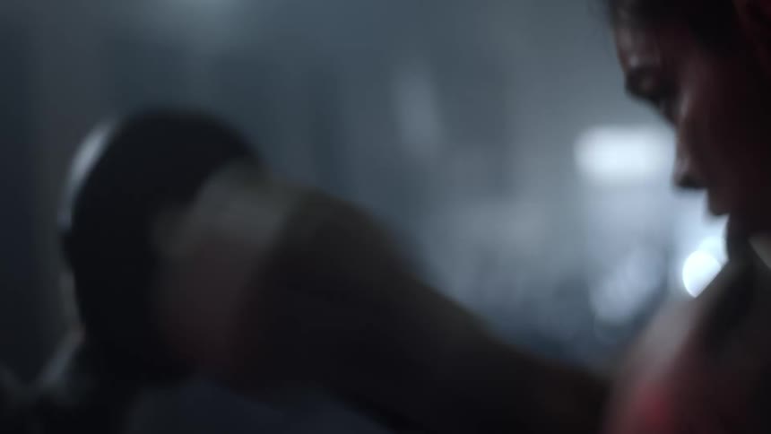 A female boxer punching and hitting pads held by another woman in a gym