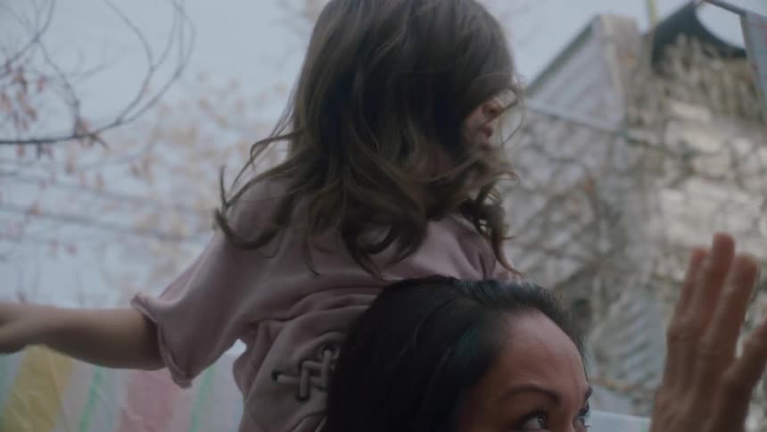 A woman lets her daughter ride on her shoulders as the tend to hanging laundry