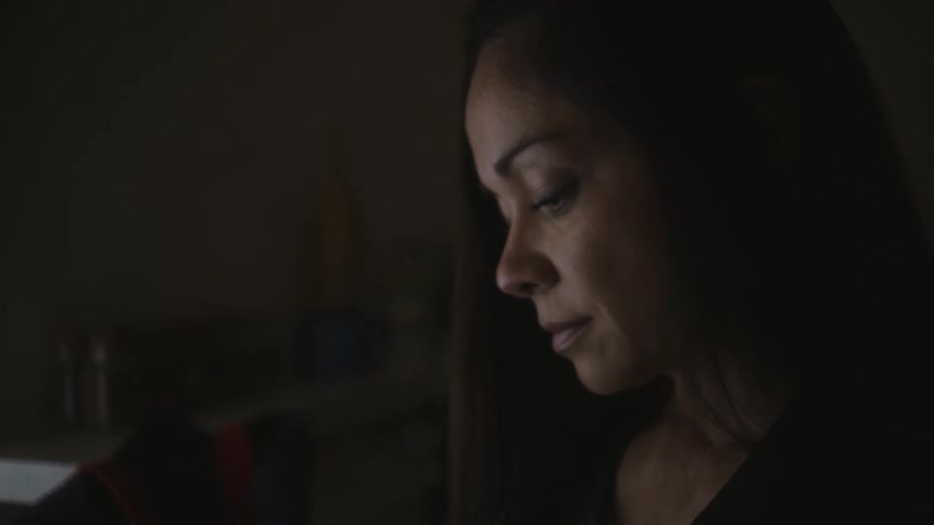 A woman sitting at her desk opening an envelope of mail while looking contemplatively