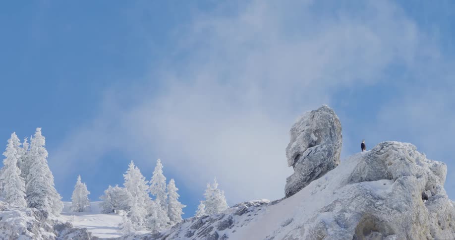 Thin clouds pass above this snow covered mountain slope