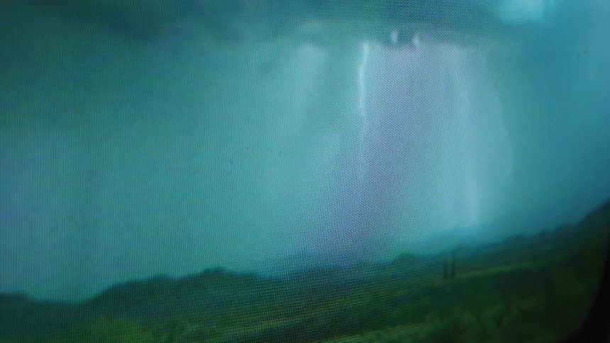 A television screen close up with a storm on it flashing lightning across the screen