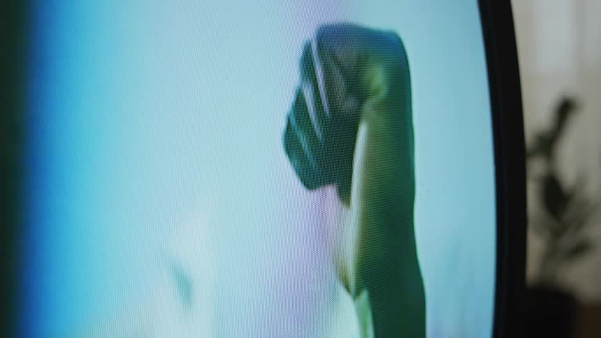 A man is shown on a television screen holding up his fist