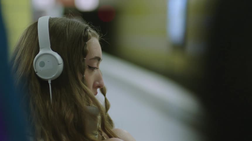 Woman wearing headphones pants as she looks around