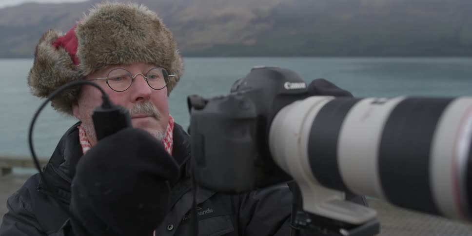 A man is using a camera near the water
