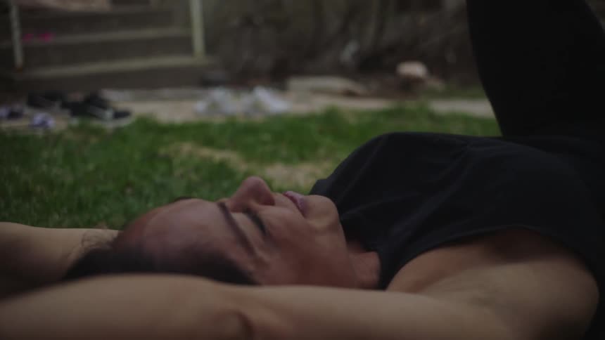 A woman holds her daughter up with her legs while playing on their front lawn