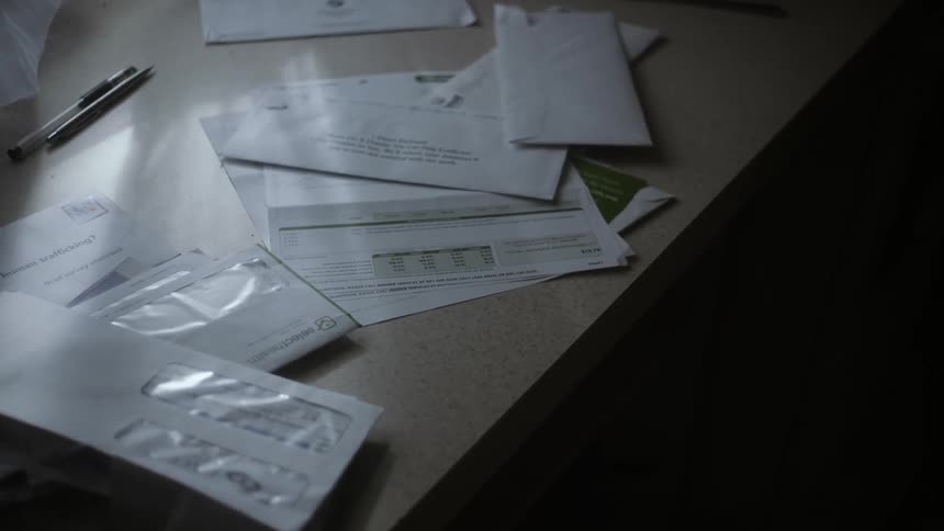 Opened and unopened mail on a table near a window