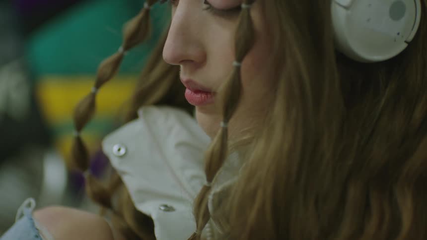 A young woman takes deep breaths and cries while wearing headphones