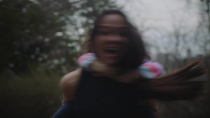 A happy mother plays with her daughter by spinning her around on piggyback