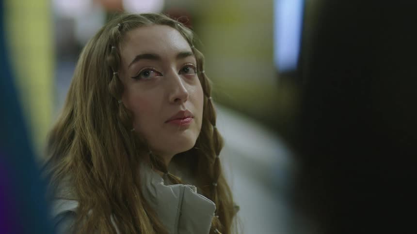 A young woman with braided hair chats with two other people nodding and smiling