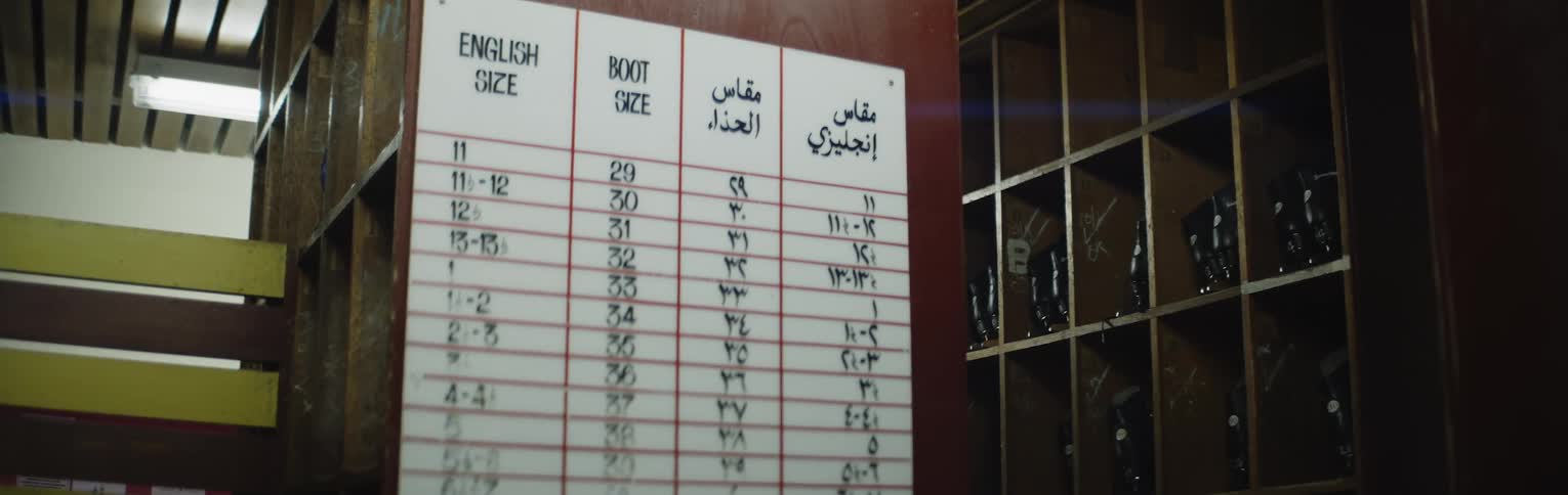 Sign on side of shelf of shoes in store lists sizes in two different languages
