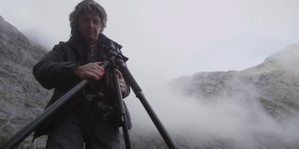 A woman is setting up a tripod