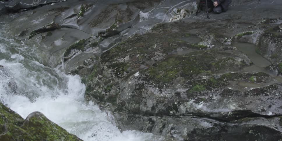 A stream is pouring water over rocks below