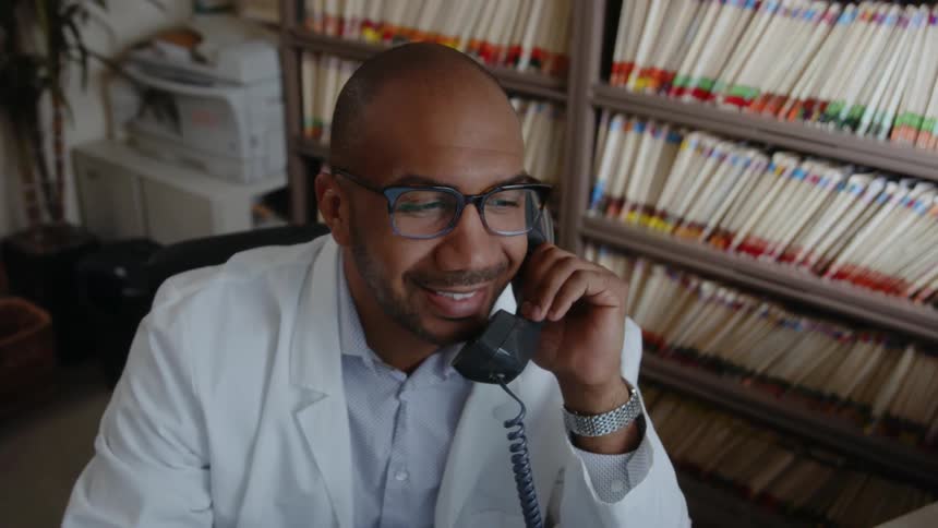 A man is talking to someone while using a telephone