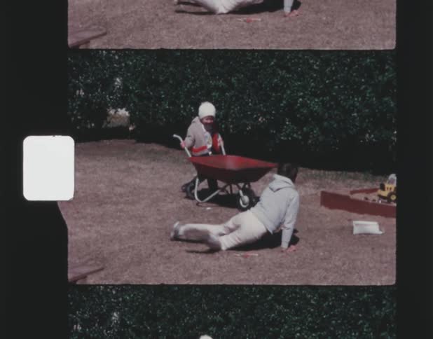 Two brothers playing outside with a wheel barrow