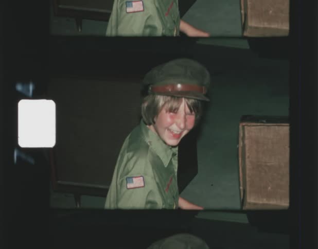 A boy tries on a vintage hat found in a wooden trunk