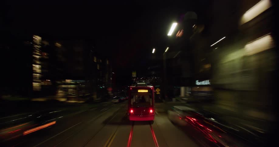 A time lapse of a trip through city traffic at night following a cable car