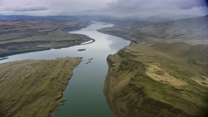 An aerial landscape of a river through a canyon with hilly and mountainous ranges on either side