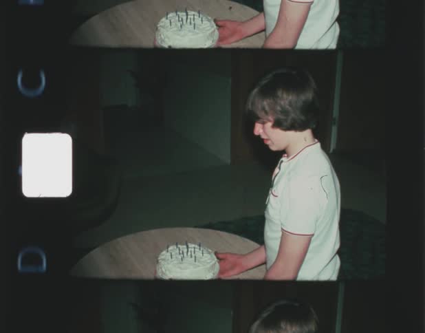 A young boy standing at a round table in front of a birthday cake with candles on it