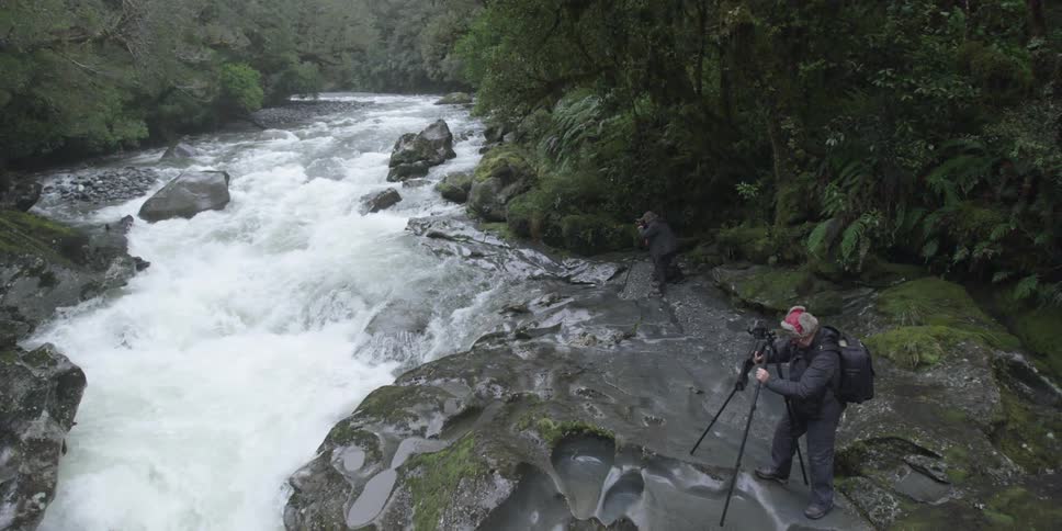 Men taking photos next to a river