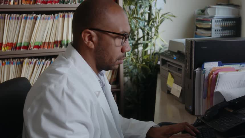 A man is sitting in his office and typing on computer