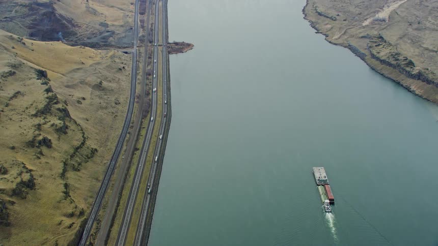 The view is of the sea and you can see on the left side cars are driving down the road