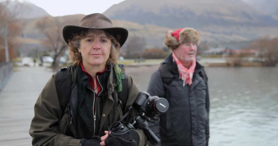 Two photographers walk next to a lake on a chilly fall day