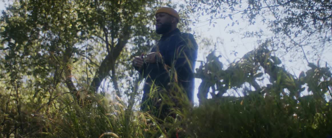 Man wearing a yellow cap stands in the backyard on a calm morning