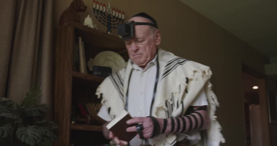 A rabbi retrieves a book from a shelf in his office