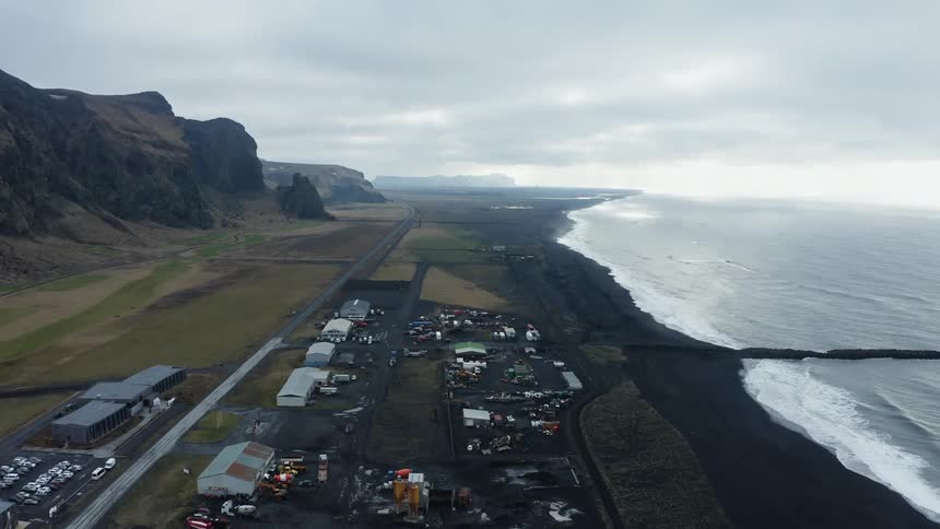 An aerial view of a coastline with buildings and offices in a remote location on an overcast day