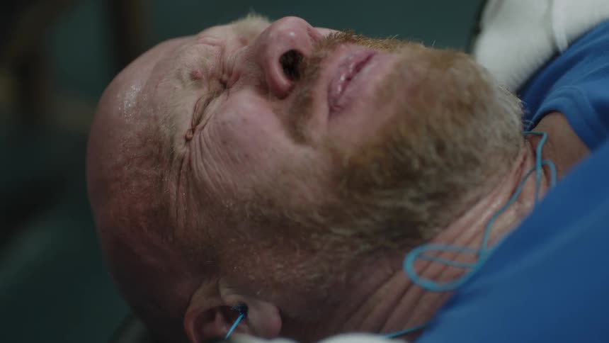 A man laying in a doctors office and wincing
