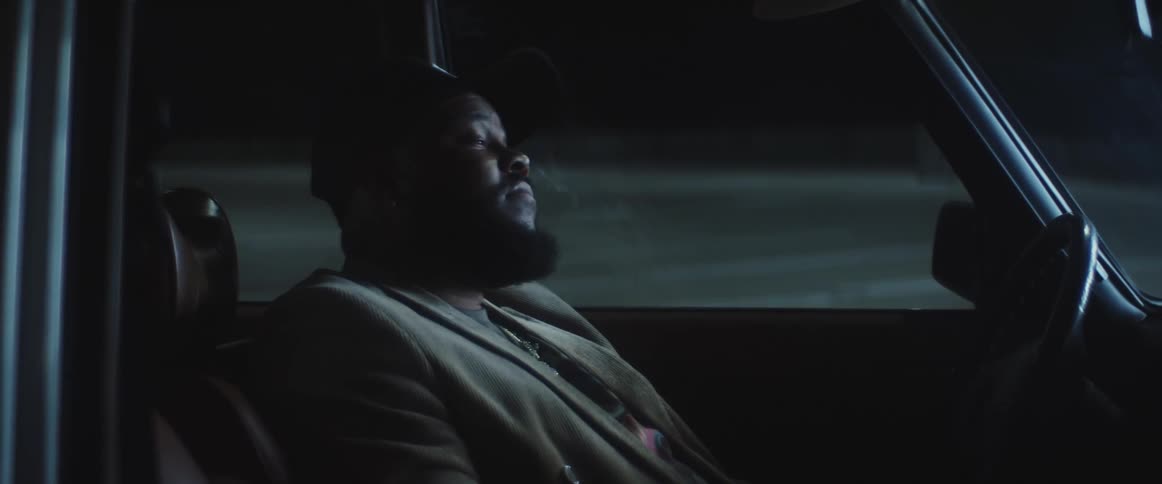 Bearded man sitting in car closes his eyes at intervals while looking through windshield