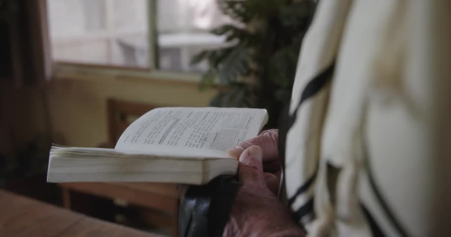 Someone is holding a book with both hands and reading from it in a room