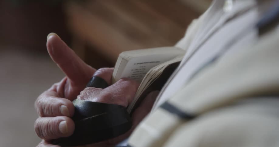 A close up of a persons hands holding a small book close to their chest