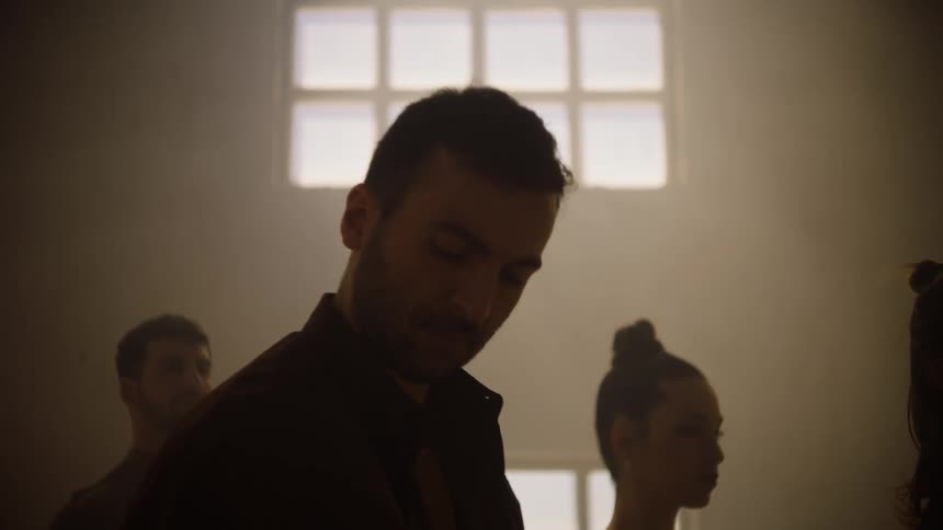Modern dancers are practicing in a shadowy dance studio during the daytime