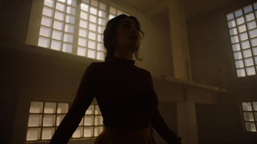 A silhouette of a woman dancing in a large empty room