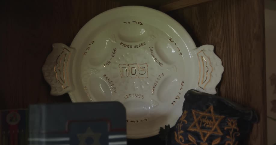 Close up of a white ceramic hebrew passover seder pesach decorative plate on a shelf