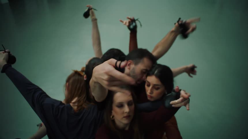 A group of dancers huddled together with their hands out clapping something between their fingers