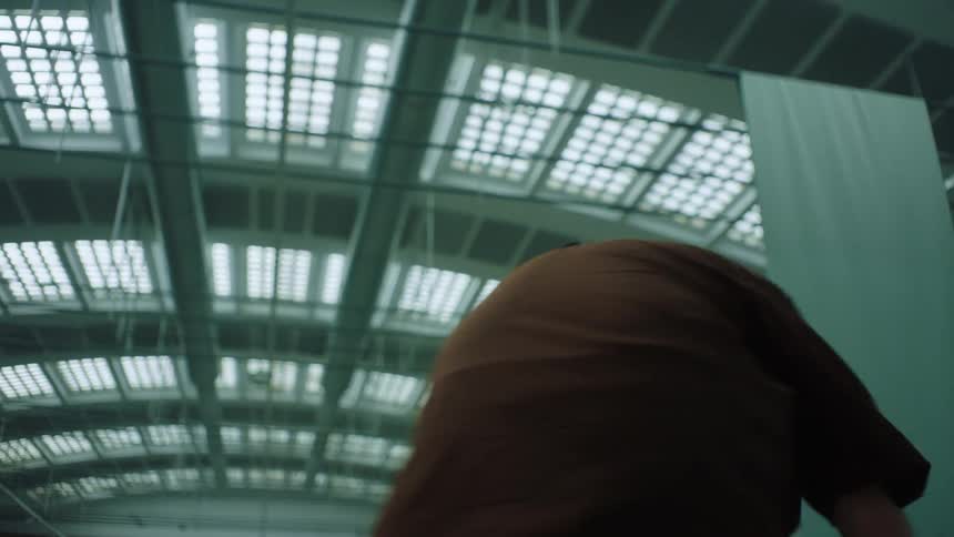 A man crouched down then spinning around laughing then falling down in a large tall building