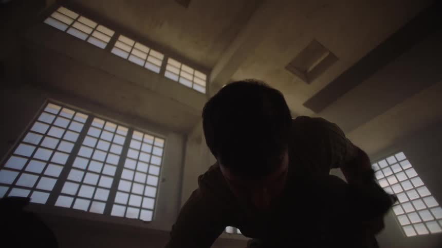 The silhouette of a man laying on the ground and then getting up and standing near another man in a large building