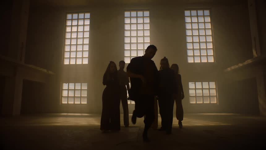 A group of peoples silhouettes dancing in a large open room