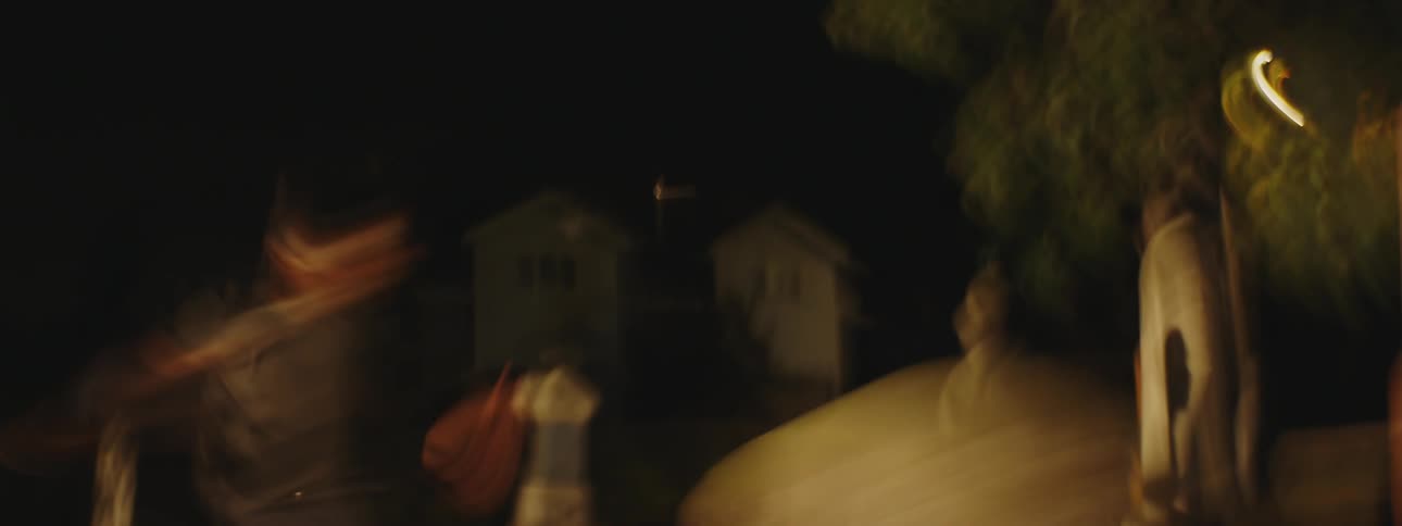 Man and woman runand leap through cemetery at night