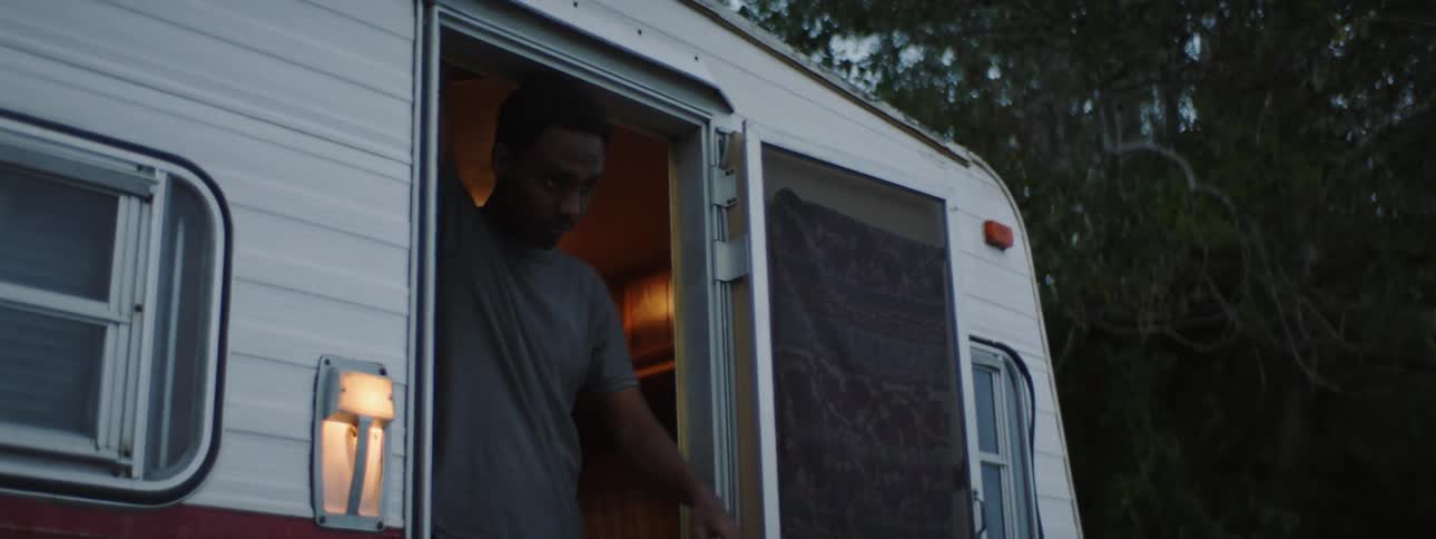 A man exits an rv and is followed by another man at dusk