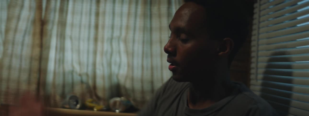 A black man is looking to his side when someone in front of him shoves him back hard