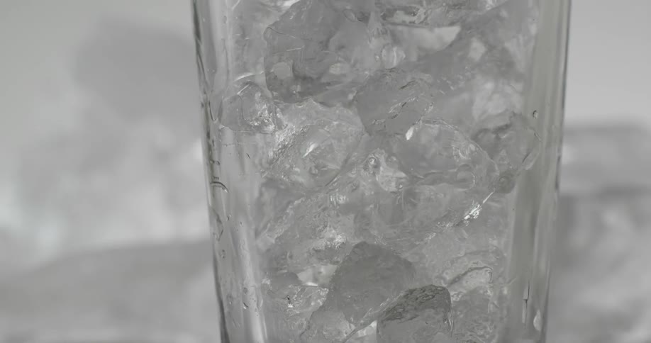 An ice block is dropping into a white glass cup
