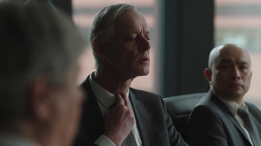 Businessman in suit takes off his glasses gulps and loosen a tie during a meeting in the office