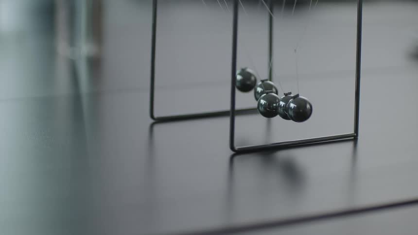 A close up of a desk toy with marbles moving back and forth