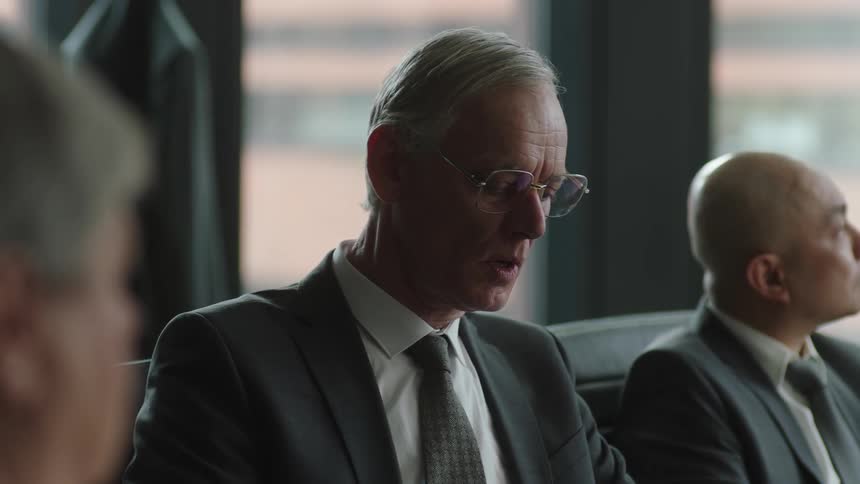 Business man puts on his glasses while attending a board meeting in the office